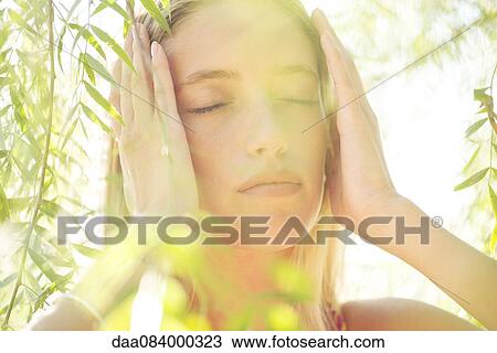 Stock Image - Woman holding head, portrait. Fotosearch