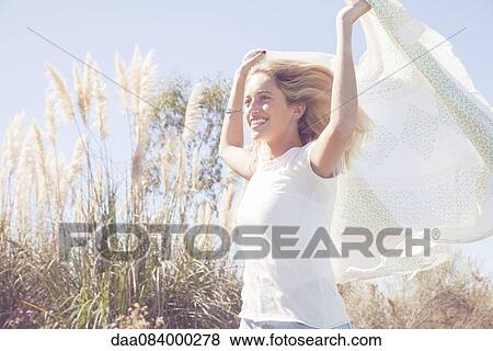 Stock Photo - Woman holding up scarf fluttering in wind. Fotosearch