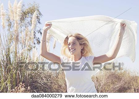Woman holding up scarf fluttering in wind View Large Photo Image Stock Photo - Woman holding up scarf fluttering in wind. Fotosearch