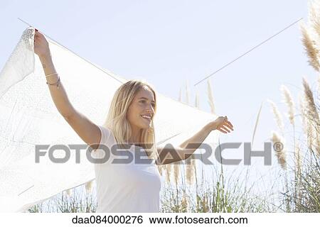 Woman holding up scarf fluttering in wind View Large Photo Image Stock Photograph - Woman holding up scarf fluttering in wind. Fotosearch