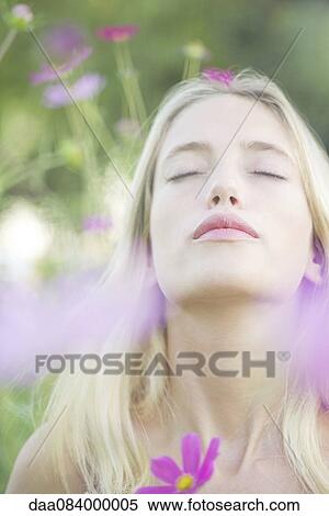 Stock Photography - Woman overwhelmed by the sweet fragrence of blooming flowers. Fotosearch