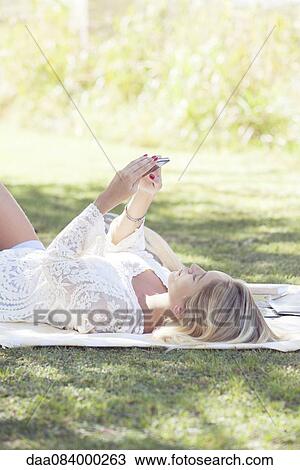 Woman relaxing in park with smartphone View Large Photo Image Stock Image - Woman relaxing in park with smartphone. Fotosearch