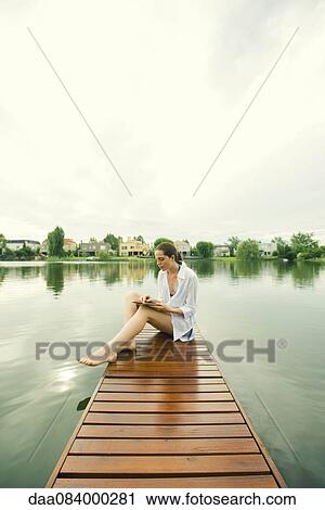 Woman sitting on lake dock using digital tablet View Large Photo Image Stock Image - Woman sitting on lake dock using digital tablet. Fotosearch