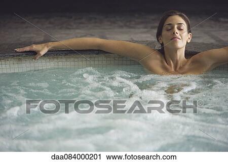 Stock Image - Woman soaking in spa pool. Fotosearch