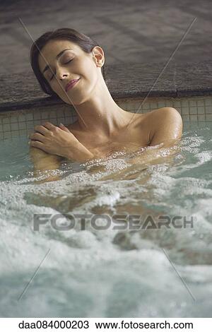 Stock Image - Woman soaking in spa pool. Fotosearch