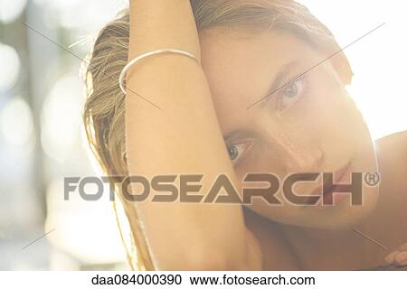 Stock Image - Woman with hand in hair, backlit. Fotosearch