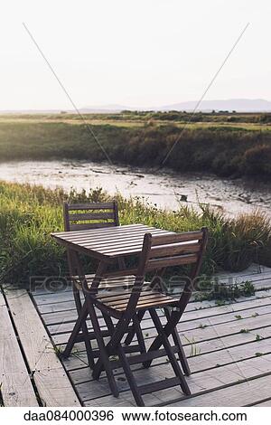 Stock Photograph - Wooden table and chairs on deck in tranquil scene. Fotosearch