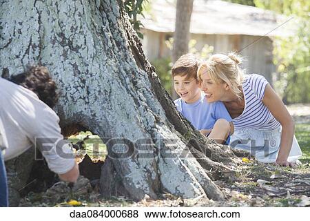 Stock Photo - Young family exploring hollowed out tree trunk. Fotosearch