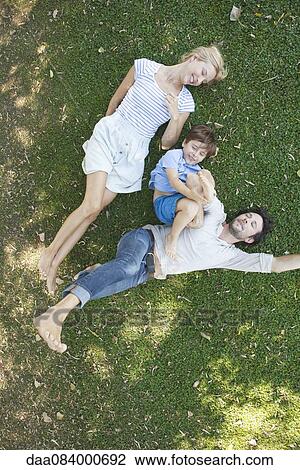 Young family with boy lying together on grass View Large Photo Image Stock Image - Young family with boy lying together on grass. Fotosearch