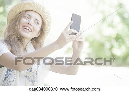 Young woman taking selfie with smartphone View Large Photo Image Stock Image - Young woman taking selfie with smartphone. Fotosearch