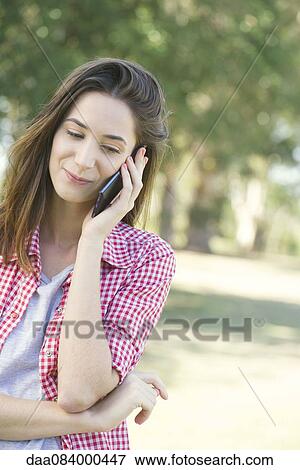 Young woman using cell phone outdoors View Large Photo Image Stock Photo - Young woman using cell phone outdoors. Fotosearch