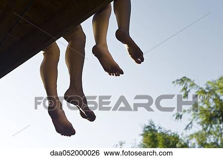 Adult and child sitting on deck with legs dangling off edge, cropped View Large Photo Image Stock Photograph - Adult and child sitting on deck with legs dangling off edge, cropped. Fotosearch