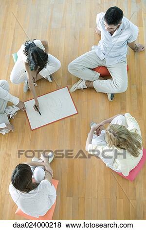 Adults sitting on cushions on floor, one woman drawing on drywipe board, high angle view View Large Photo Image Stock Photo - Adults sitting on cushions on floor, one woman drawing on drywipe board, high angle view. Fotosearch