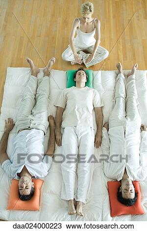 Alternative therapy session, three adults lying side by side while therapist puts hands out over man's head View Large Photo Image Stock Image - Alternative therapy session, three adults lying side by side while therapist puts hands out over man's head. Fotosearch
