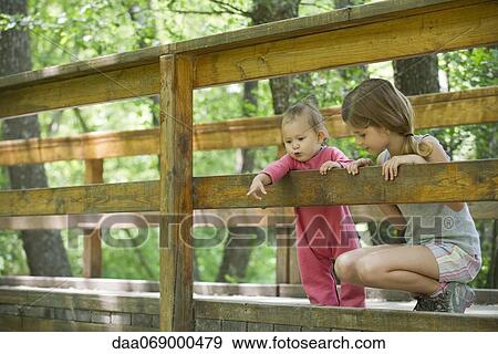 Baby girl and older sister looking over railing of bridge View Large Photo Image Stock Photo - Baby girl and older sister looking over railing of bridge. Fotosearch