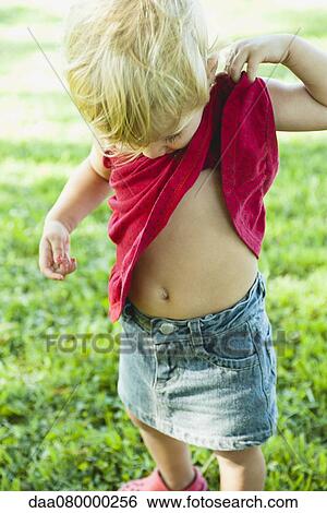 Stock Photograph - Baby girl lifting shirt up, looking curiosly at abdomen. Fotosearch