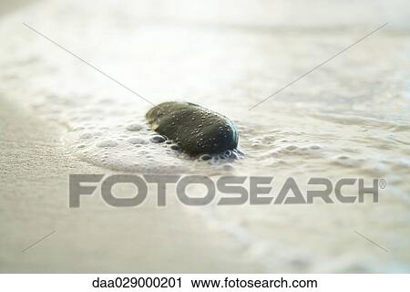 Stock Image - Beach pebble and surf, close-up. Fotosearch