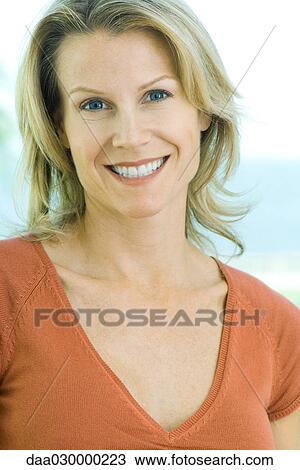 Stock Image - Blonde woman smiling at camera, portrait. Fotosearch