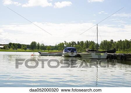 Boats docked near lake pier View Large Photo Image Stock Image - Boats docked near lake pier. Fotosearch