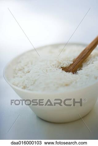 Stock Image - Bowl of rice and wooden spoon. Fotosearch