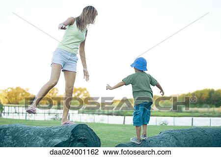 Stock Image - Boy and mother balancing on logs. Fotosearch