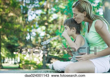 Boy and mother blowing bubbles, side view View Large Photo Image Stock Image - Boy and mother blowing bubbles, side view. Fotosearch