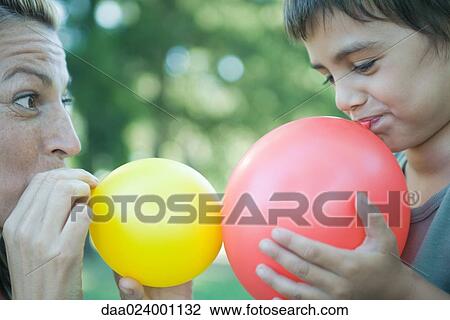 Stock Image - Boy and mother blowing up balloons. Fotosearch