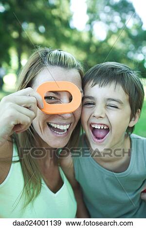 Boy and mother, woman looking through toy shape, both laughing and looking at camera View Large Photo Image Stock Photo - Boy and mother, woman looking through toy shape, both laughing and looking at camera. Fotosearch