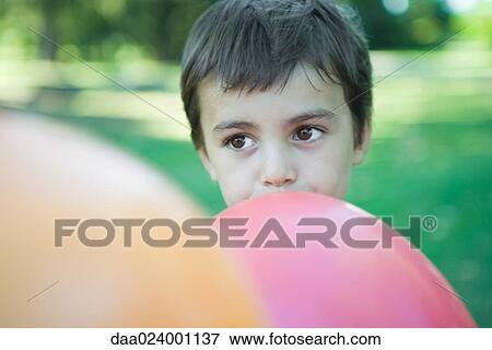 Stock Photo - Boy blowing up balloon. Fotosearch