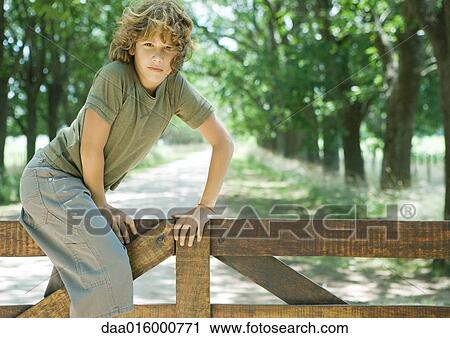 Boy climbing fence, looking at camera View Large Photo Image Stock Image - Boy climbing fence, looking at camera. Fotosearch