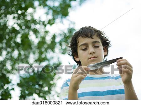 Boy holding feather, low angle view View Large Photo Image Stock Image - Boy holding feather, low angle view. Fotosearch