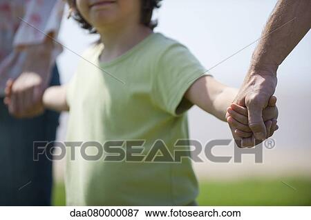 Boy holding hands with parents, cropped View Large Photo Image Stock Photo - Boy holding hands with parents, cropped. Fotosearch