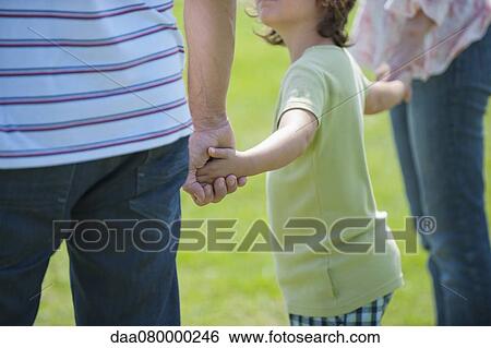 Stock Photograph - Boy holding hands with parents, cropped. Fotosearch