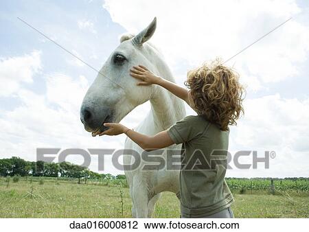 Stock Image - Boy petting horse. Fotosearch