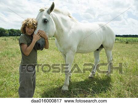 Boy standing cheek to cheek with horse View Large Photo Image Stock Photo - Boy standing cheek to cheek with horse. Fotosearch
