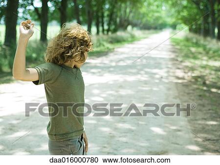 Boy standing in middle of dirt road, throwing pebbles View Large Photo Image Stock Image - Boy standing in middle of dirt road, throwing pebbles. Fotosearch