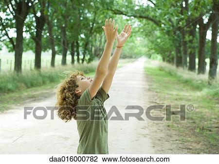 Boy standing in middle of dirt road, arms raised View Large Photo Image Stock Image - Boy standing in middle of dirt road, arms raised. Fotosearch