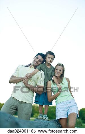 Boy standing on log, between mother and father, smiling at camera View Large Photo Image Stock Photography - Boy standing on log, between mother and father, smiling at camera. Fotosearch