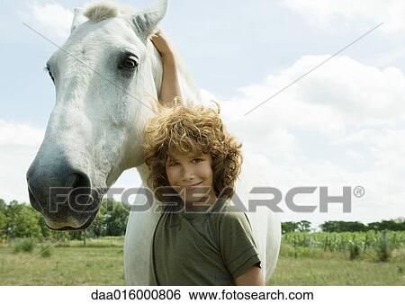 Boy standing with arm around horse View Large Photo Image Stock Photograph - Boy standing with arm around horse. Fotosearch