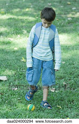 Boy wearing backpack, poised to kick ball View Large Photo Image Picture - Boy wearing backpack, poised to kick ball. Fotosearch