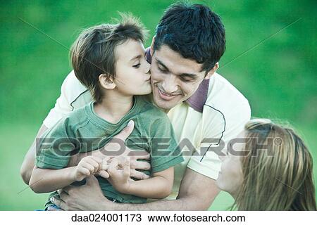 Stock Image - Boy with parents, kissing father on cheek. Fotosearch
