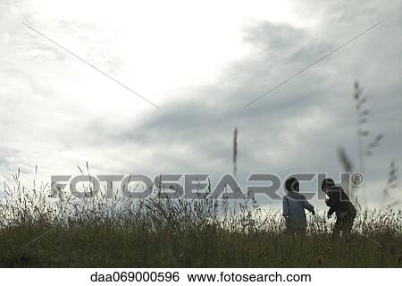 Stock Photograph - Boys playing on meadow, rear view. Fotosearch