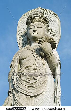 Stock Image - Buddha statue, low angle view. Fotosearch