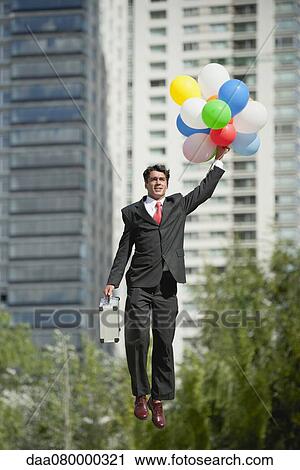Businessman being carried away by bunch of balloons View Large Photo Image Stock Image - Businessman being carried away by bunch of balloons. Fotosearch