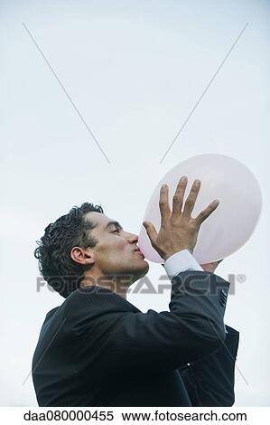 Businessman blowing up balloons View Large Photo Image Stock Photography - Businessman blowing up balloons. Fotosearch