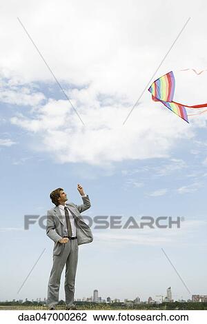 Businessman flying kite in field View Large Photo Image Stock Image - Businessman flying kite in field. Fotosearch