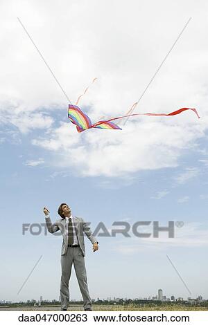 Businessman flying kite in field View Large Photo Image Stock Image - Businessman flying kite in field. Fotosearch