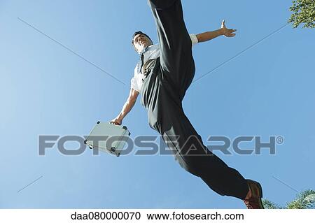 Businessman jumping in air carrying briefcase, low angle view View Large Photo Image Stock Image - Businessman jumping in air carrying briefcase, low angle view. Fotosearch