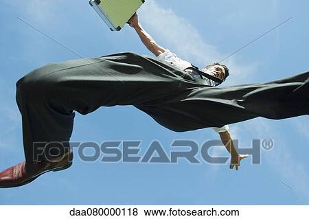 Businessman jumping in air carrying briefcase, directly below View Large Photo Image Stock Photo - Businessman jumping in air carrying briefcase, directly below. Fotosearch