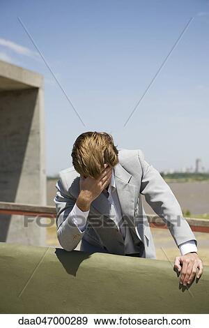 Businessman leaning against wall holding head View Large Photo Image Stock Photo - Businessman leaning against wall holding head. Fotosearch